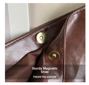 Detailed macro view of the gold magnetic closure on a brown leather tote bag