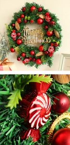 Detailansicht künstlicher Kiefernzweige mit roten Kugeln und Merry Christmas Schild