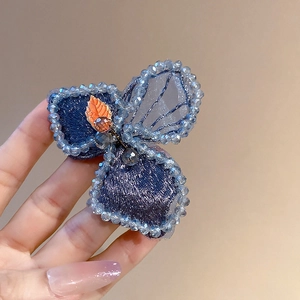 Detailed close-up of blue petal hair clip with embroidery and light blue beads