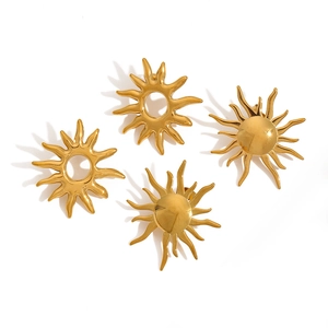 Detailed view of four golden sun-shaped stainless steel earrings on a white background
