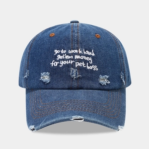 Distressed dark blue denim baseball cap with white embroidery on a light grey background