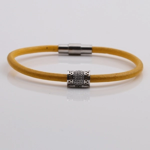 Dettaglio del bracciale in corda gialla intrecciata con charm in argento e zirconi