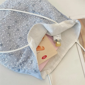 Close-up of light blue floral canvas bag with white pearl mesh overlay and spacious interior