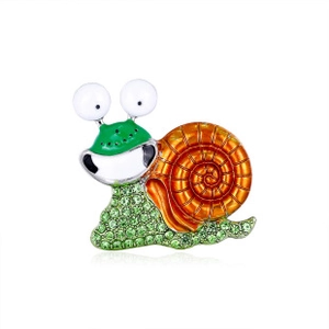 Macro shot of snail brooch with green rhinestones and golden spiral enamel detail