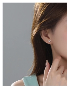 Close-up of minimalist silver butterfly stud earring worn on ear for elegant daily style