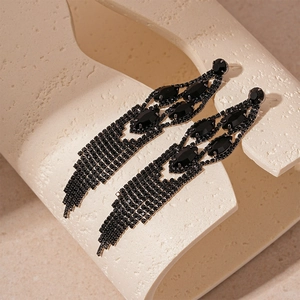 Detailed close-up of dark rhinestone geometric tassel earrings on a stone display