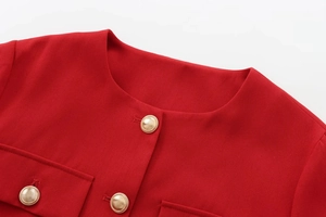Detail of red crew neck jacket featuring textured gold buttons and premium fabric finish