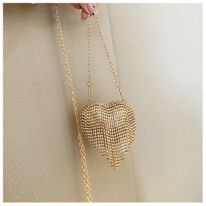 Close-up of golden heart-shaped evening bag with sparkling rhinestones and tassels