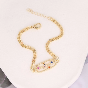 Detail of gold chain bracelet with colorful gemstones and star and moon charm motifs