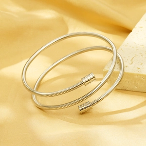 Silver double-layered cable spring bracelet on a beige stone with yellow silk background