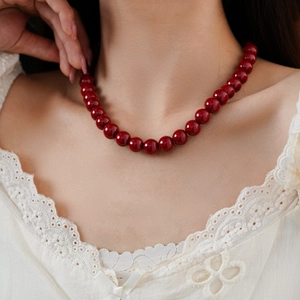 Close-up of elegant red glass bead necklace with high glossy finish on a female model