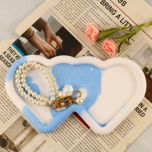 Dettaglio di un vassoio portagioie a cuore marmorizzato blu con bracciale di perle