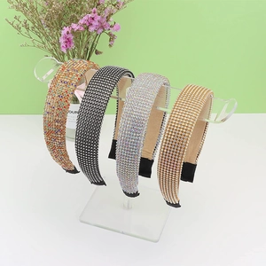 Detail showing four sparkling rhinestone headbands displayed on a clear acrylic rack