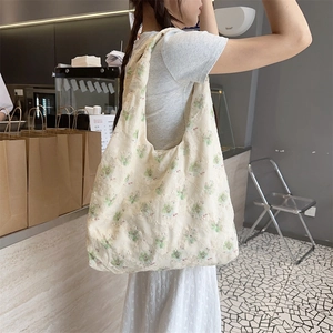 Close-up of delicate floral embroidery on cream canvas tote bag with textured cotton fabric