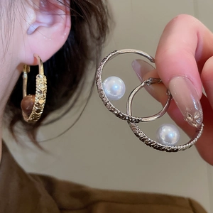 Detailed view of twisted metal hoop earrings with pearl accents in gold and silver