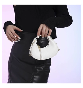 Detail of white crescent moon bag with textured leather and gold-tone hardware