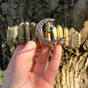 Macro view of gold raw crystal crown with crescent moon and star pendant charms