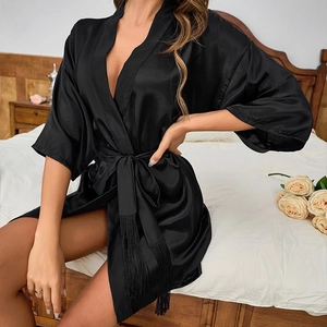 Elegant black satin kimono bathrobe for women featuring fringed belt in bedroom setting