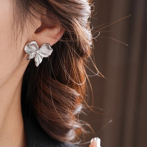 Close-up of a silver flower earring with crystal center worn by a female model