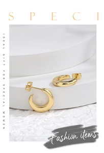 Detail shot of high-polished gold C-shaped earrings on a minimalist white pedestal