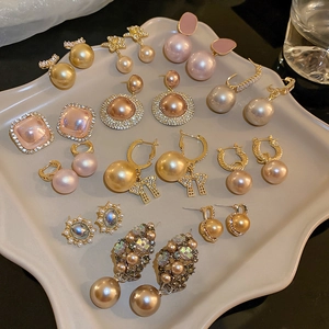 Close-up of pearl and zircon geometric earrings on a beige tray with golden bows