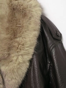Gros plan détaillé de la veste en cuir marron avec col en fourrure et texture grainée