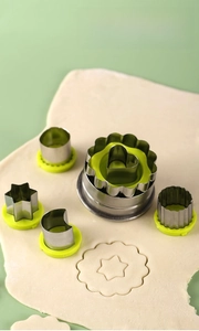 Set of six stainless steel hollow cookie cutters with green bases for baking crafts