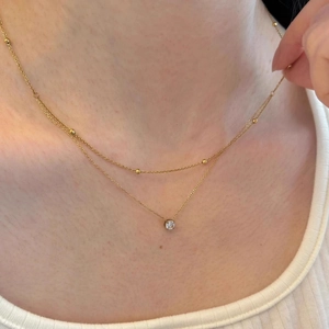 Double-layered gold necklace with sparkling zircon pendant and delicate beads on chain