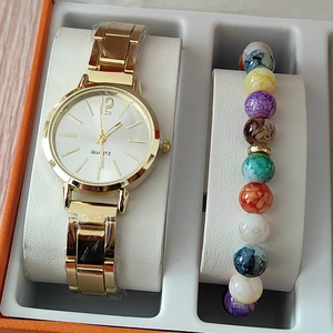 Close-up of a gold quartz watch and colorful beaded bracelet set in a gift box