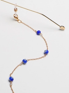 Dettaglio catena per occhiali dorata con perline occhio blu e ganci in silicone