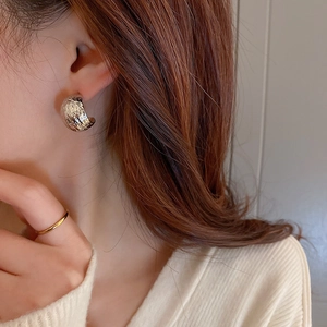 Silver metallic C-shaped earrings with hammered texture shown on model for a modern look