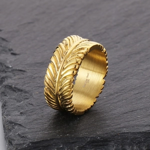 Detail view of gold feather texture ring on slate with 316L stainless steel engraving