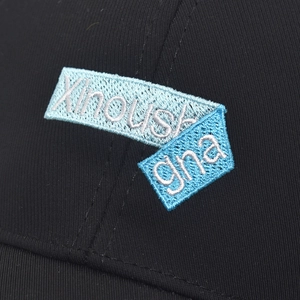 Detailansicht der blauen Xinoush-Stickerei auf der schwarzen Baumwoll-Baseballkappe