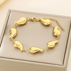 Detailed close-up of golden stainless steel bracelet with teardrop charms on jewelry box