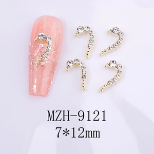 Macro detail of J-shaped gold nail art charms with white rhinestones, size 7x12mm