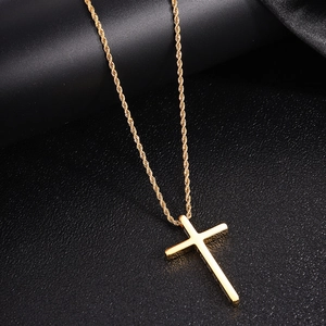 Polished gold cross pendant with twisted chain on a dark textured surface