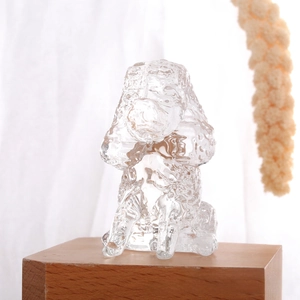 Macro detail of a crystal glass puppy ornament on a wooden base with warm lighting