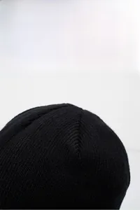 Detailed view of the vertical ribbed knit texture and stitching on a black beanie cap