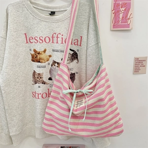 Détail du sac cabas en toile rayée rose avec un nœud vert et une étiquette tissée