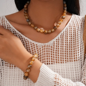 Detail of bohemian amber-toned acrylic beaded necklace and bracelet set on a model