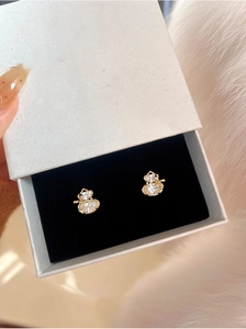 Macro shot of gold-plated gourd earrings with white zircon in a premium jewelry gift box