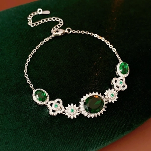 Detailed close-up of emerald floral bracelet on a green velvet vintage jewelry box