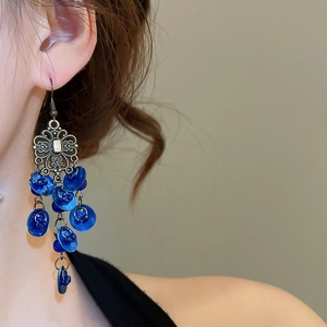 Detail of vintage bohemian shell tassel earrings with blue discs and silver metal