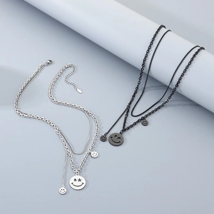 Detail of layered smile face necklaces in silver and black metal with star-eye pendants