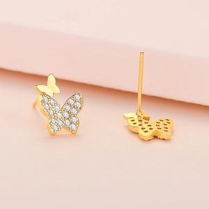 Elegant gold butterfly stud earrings with white zircon stones on soft background