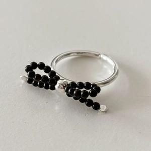 Macro shot of 925 sterling silver bow ring with black beads on grey background