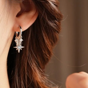 Close-up of sparkling star-shaped zircon pendant earring worn by a model