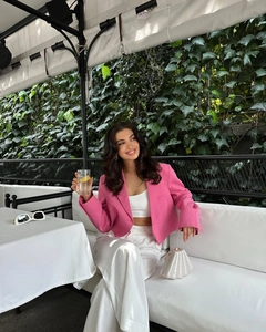 Detail of a pink cropped blazer and satin wide-leg trousers for a stylish resort look