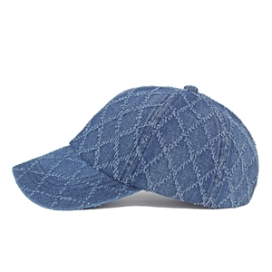 Détail de la casquette en jean bleue avec coutures en losanges et bords effilochés