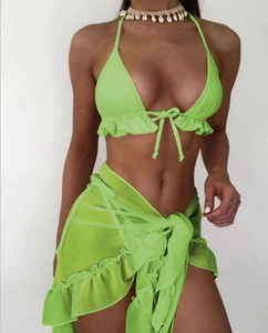 Dettaglio del top bikini verde neon con pareo in rete a balze e collana di conchiglie